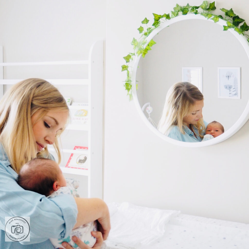 Mum holding newborn looking into mirror