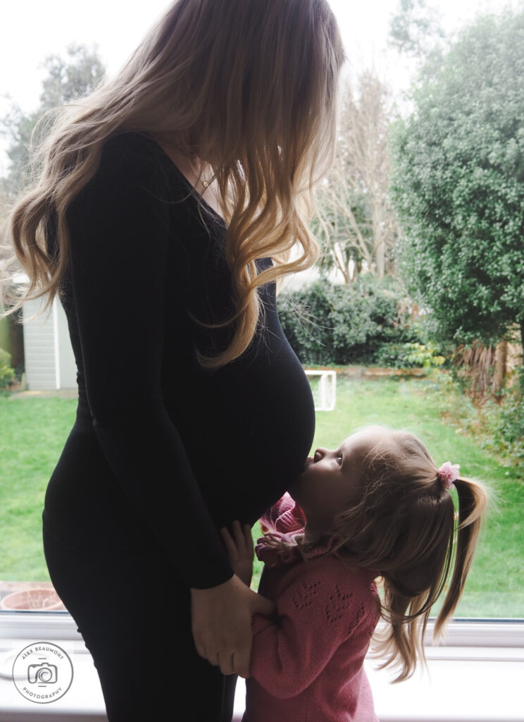 Toddler kisses mum's pregnant tummy