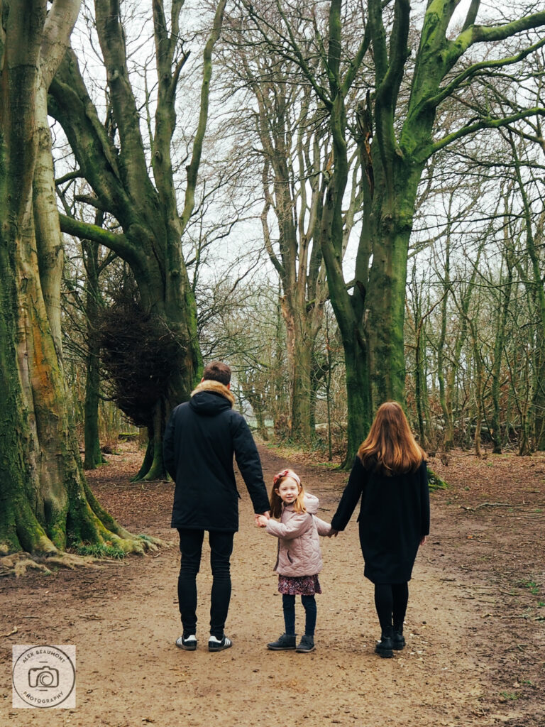 Parent's and daughter walking in woodland