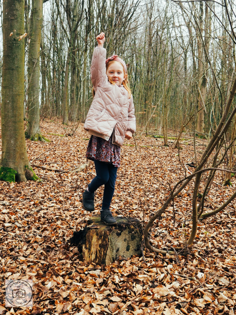 Girl posing as superman in wood