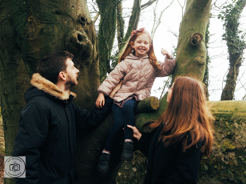 Girl sitting in tree with parents