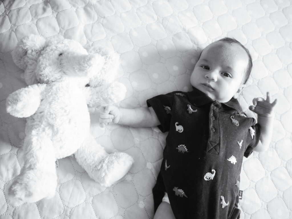 Baby lying on bed with teddy