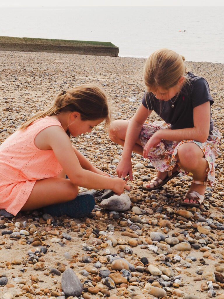 Sisters playing with pebbles on beach
