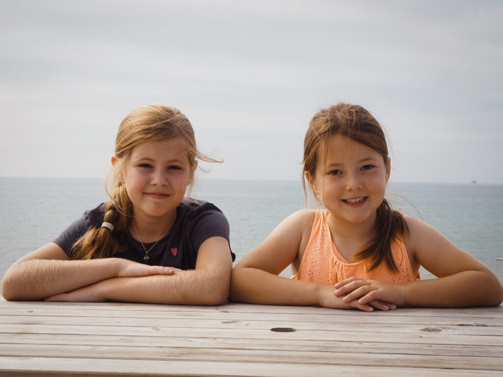 Sisters smiling at camera with sea in background