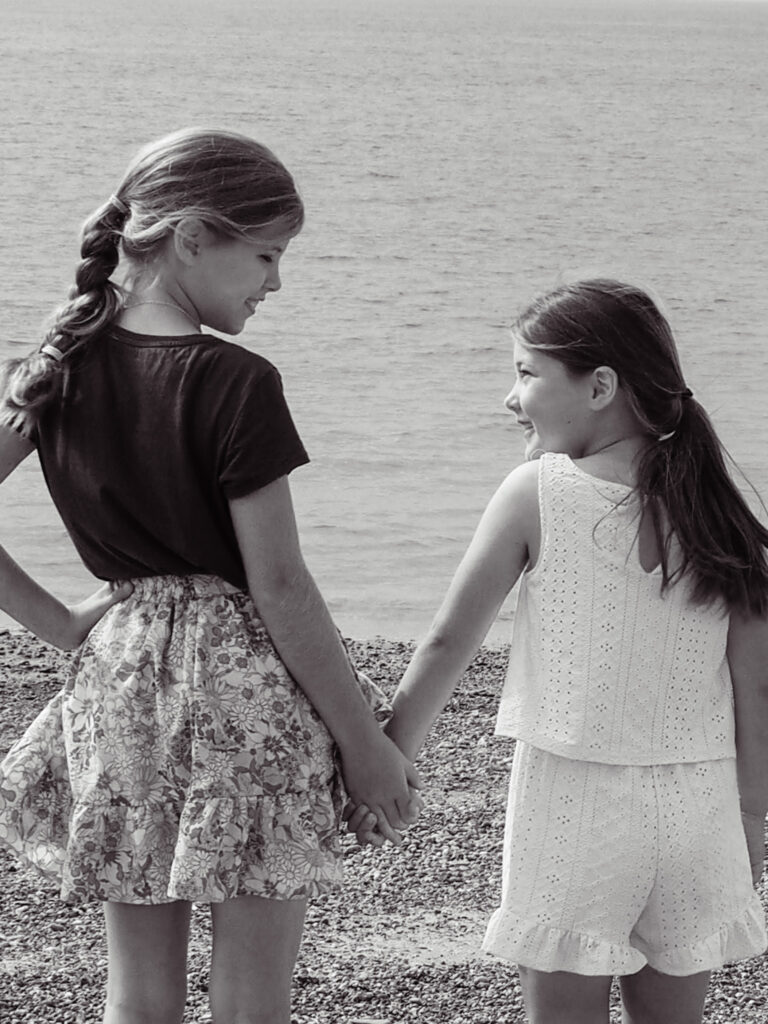 Sisters holding hands standing on beach