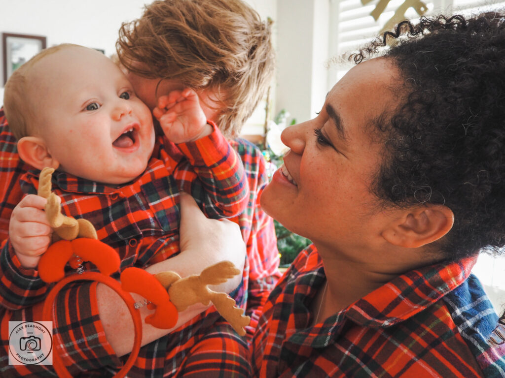 Dad snuggling baby with mum smiling all wearing Christmas pyjamas