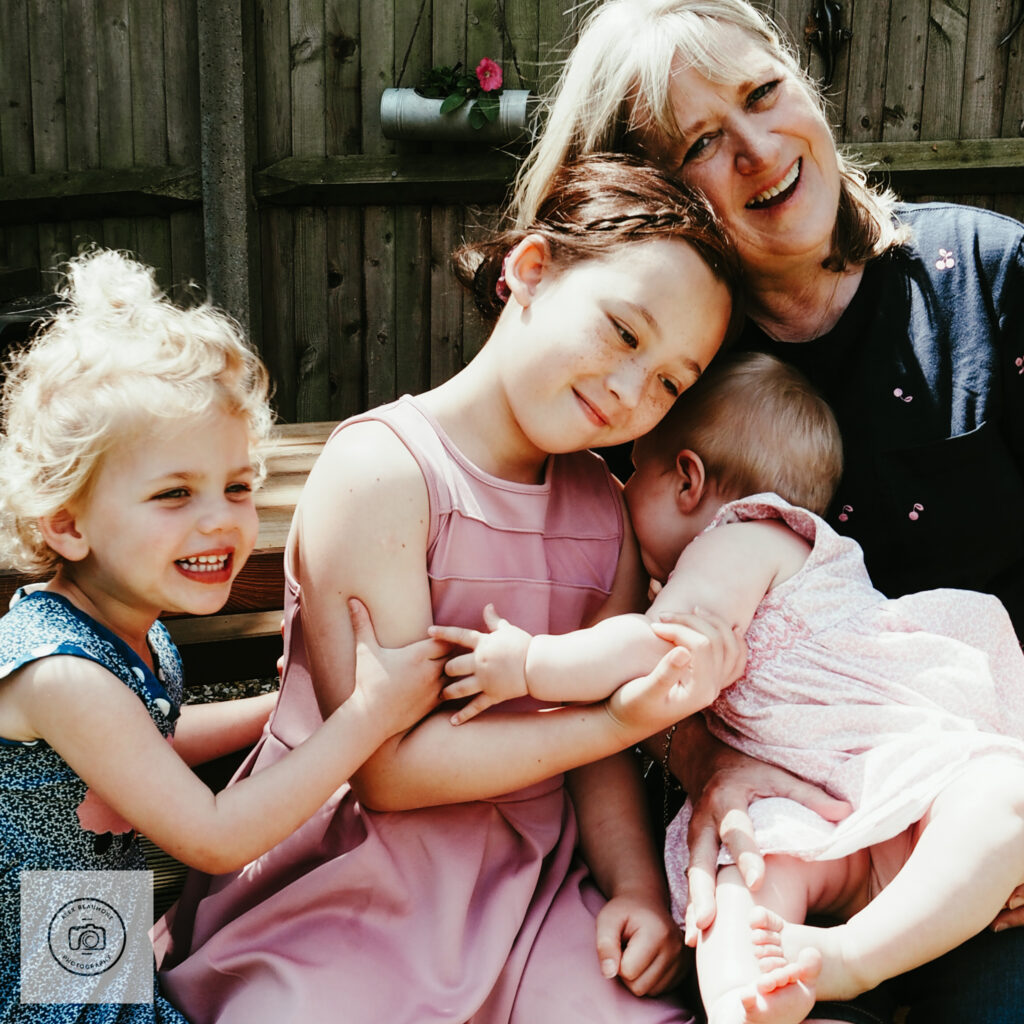 Grandmother sitting with three granddaughters in garden
